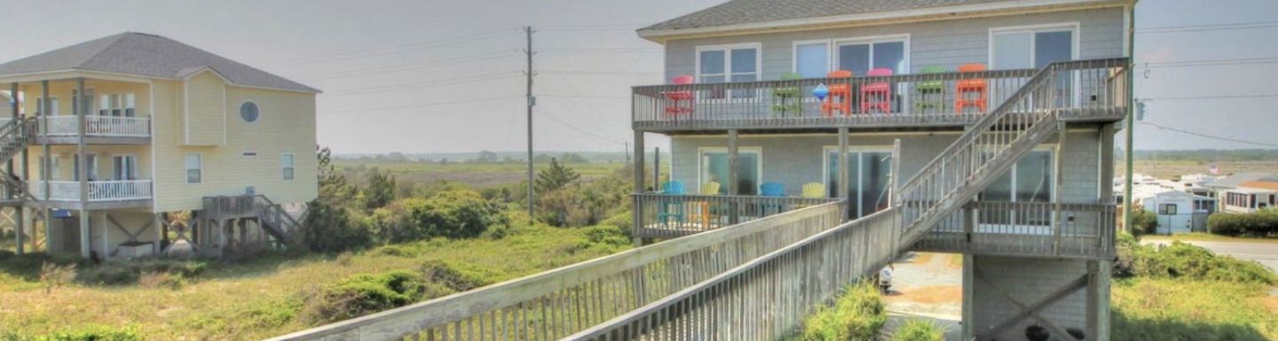 Beach house with brightly colored chairs on upper deck representing a Plum CoOwnership fractional ownership vacation home